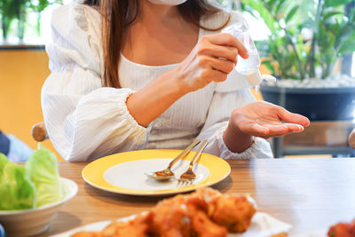 Woman apply hand sanitizer before eating in restaurant for disinfection virus, bacteria and germs. 