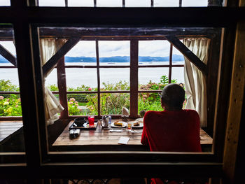 Rear view of woman looking through window