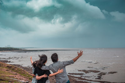 Rear view of people on beach against sky