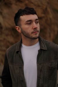 Close-up of young man looking away against wall