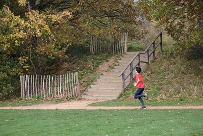 Full length of woman running on footpath amidst plants