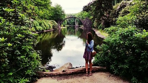 Rear view of girls on lake by trees