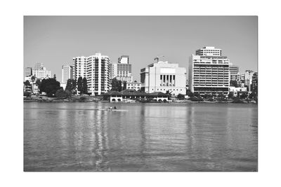 Buildings by river against sky in city