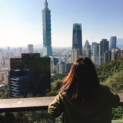 Rear view of woman standing against modern buildings in city