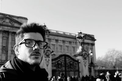 Close-up portrait of man standing against buckingham palace