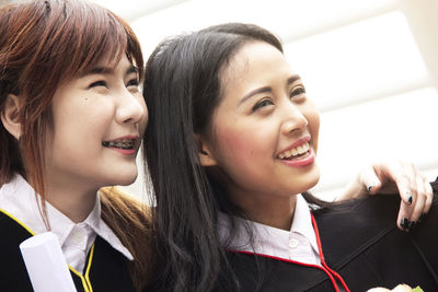 Close-up of cheerful female students wearing graduation gowns