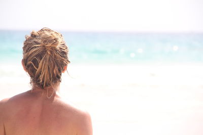 Rear view of woman on beach against sky