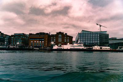 Buildings by river against sky in city