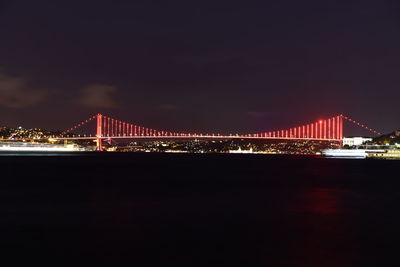 Illuminated golden gate bridge over sea against sky at night
