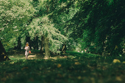 Full length of woman walking amidst trees in forest