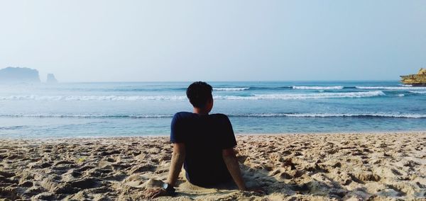 Rear view of woman looking at sea against clear sky