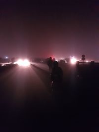 Silhouette people standing on illuminated street at night