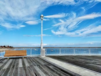 Street lights on pier by sea against blue sky