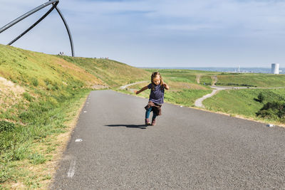 Full length of girl running on road against sky