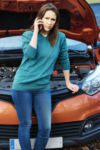 Full length of woman with umbrella standing in car