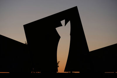 Low angle view of silhouette sign against sky during sunset