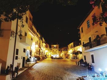 Illuminated street amidst buildings at night