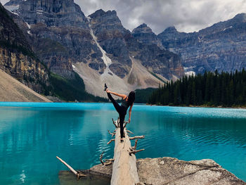 Man on rock by lake against mountains