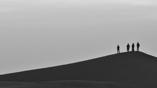 Silhouette people standing at desert against sky