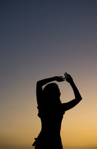 Rear view of silhouette woman standing against sky during sunset