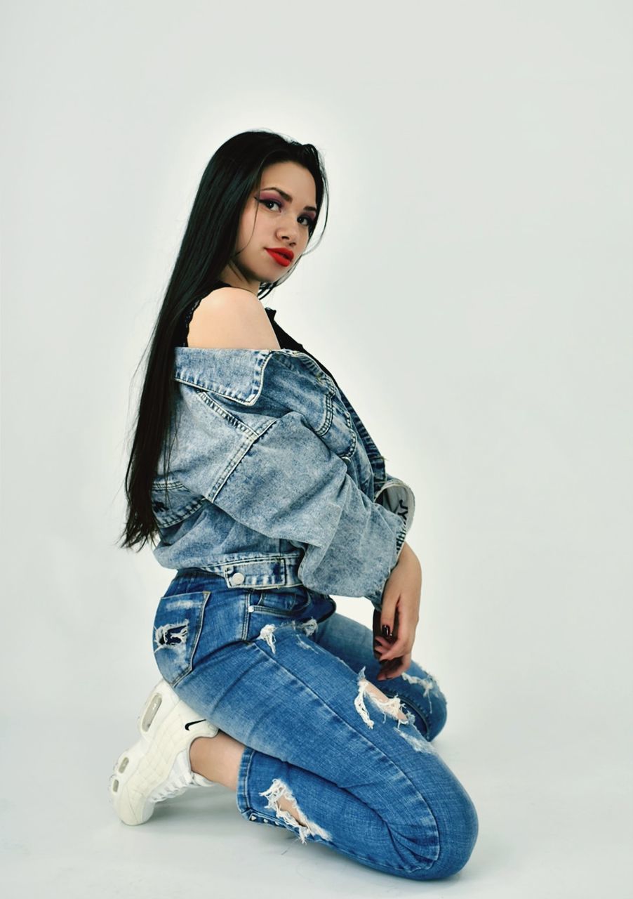 one person, blue, jeans, casual clothing, studio shot, women, adult, photo shoot, denim, portrait, young adult, full length, indoors, fashion, clothing, long hair, hairstyle, white background, sitting, looking at camera, female, spring, child, textile, shoe, lifestyles, outerwear, emotion, copy space, brown hair, cut out, looking, side view