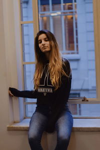 Beautiful young woman standing against wall