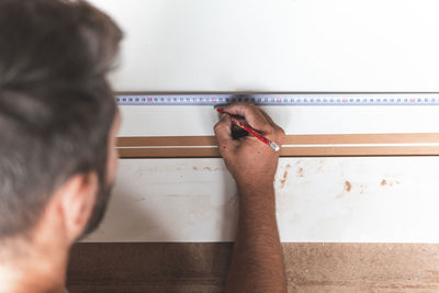 Young male carpenter marking on wood using tape measure while working in workshop