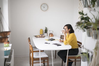 Woman drinking at dining table