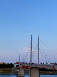 Suspension bridge over river against clear blue sky