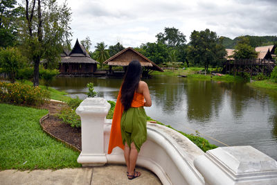 Woman with umbrella on lake against sky