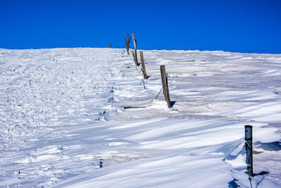 Wooden poles submerged by the snow crystallized by the wind monte grappa, vicenza, italy