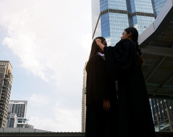 Low angle view of friends standing against buildings in city