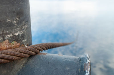 Close-up of rope tied to bollard against sky