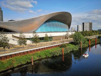 Bridge over river by modern buildings against sky