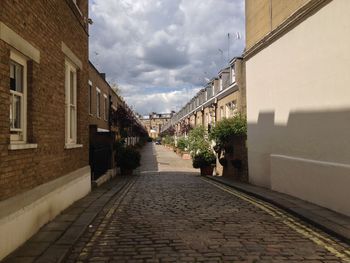 Walkway amidst buildings in city against sky