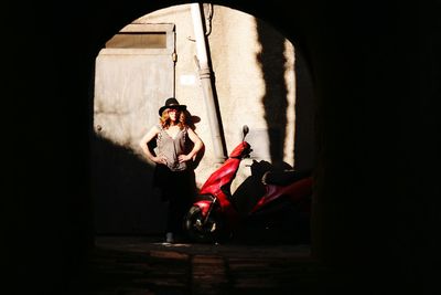 Full length of woman wearing hat standing against wall