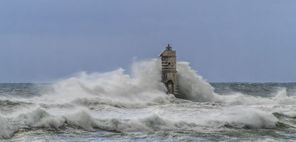 Waves splashing on shore against clear sky