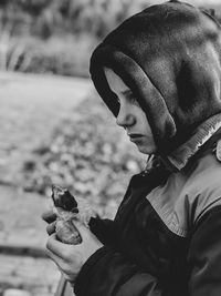 A ten-year-old boy in a hood eats a pie on the street