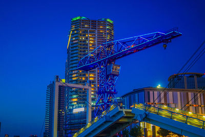 Low angle view of illuminated crane against sky at night