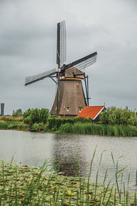 Windmill with house aside canal in a cloudy day at kinderdijk. a polder the country of netherlands.