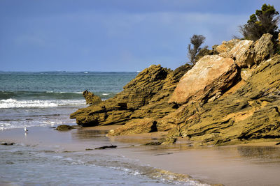 Rock formation on beach against sky