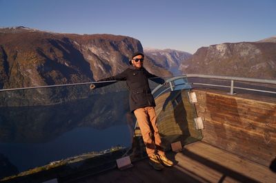 Man standing on railing against mountains