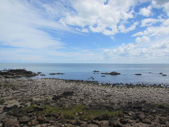 Scenic view of beach against cloudy sky