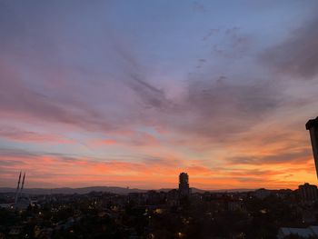 Cityscape against dramatic sky during sunset