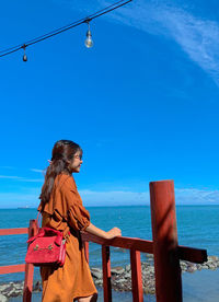 Woman standing by sea against sky