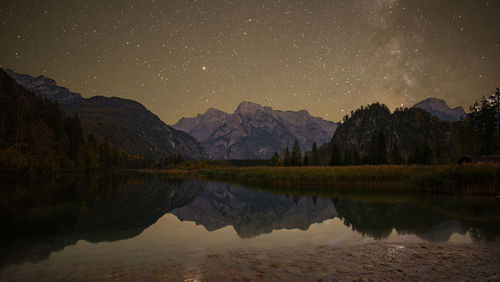 Scenic view of lake and mountains against sky at night