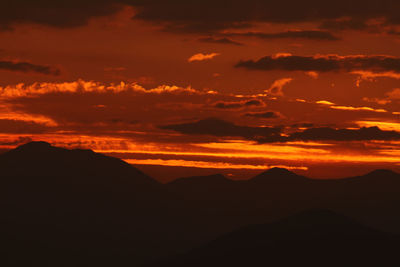 Scenic view of silhouette mountains against orange sky