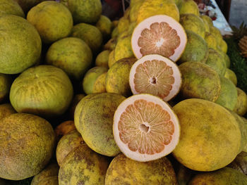 Halves of fresh pomelo fruit on a pile for sale