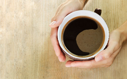 Directly above shot of hand holding coffee cup