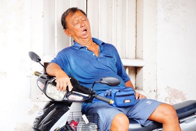 Portrait of man sitting against wall